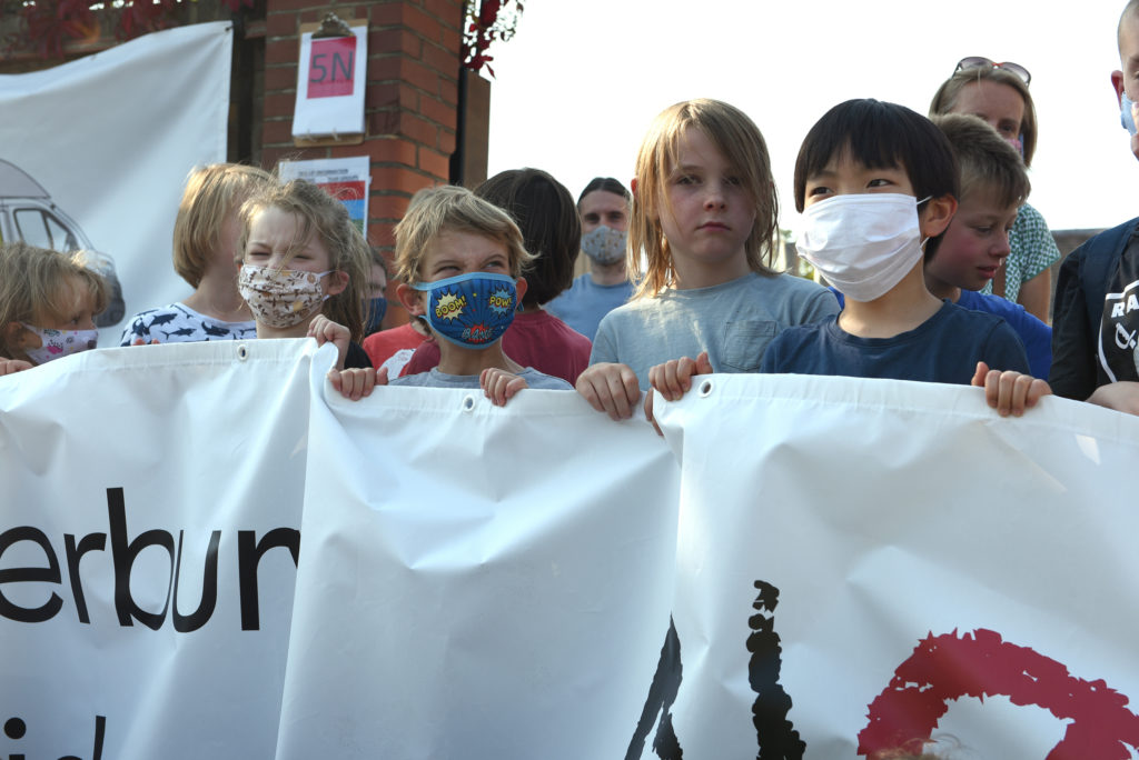 kids holding a big banner and wearing face masks