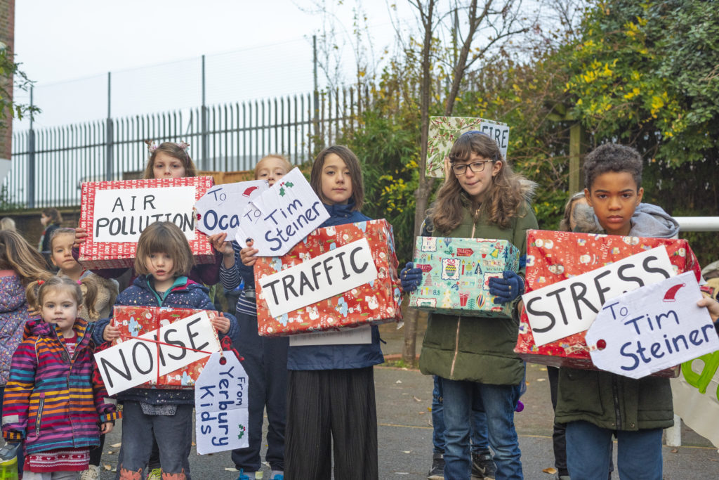 kids holding up Christmas presents to Ocado labelled air pollution, noise, traffic, stress, fire risk