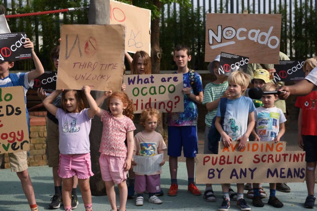 Group of children holding signs including What are Ocado hiding? and Avoiding public scrutiny by any means