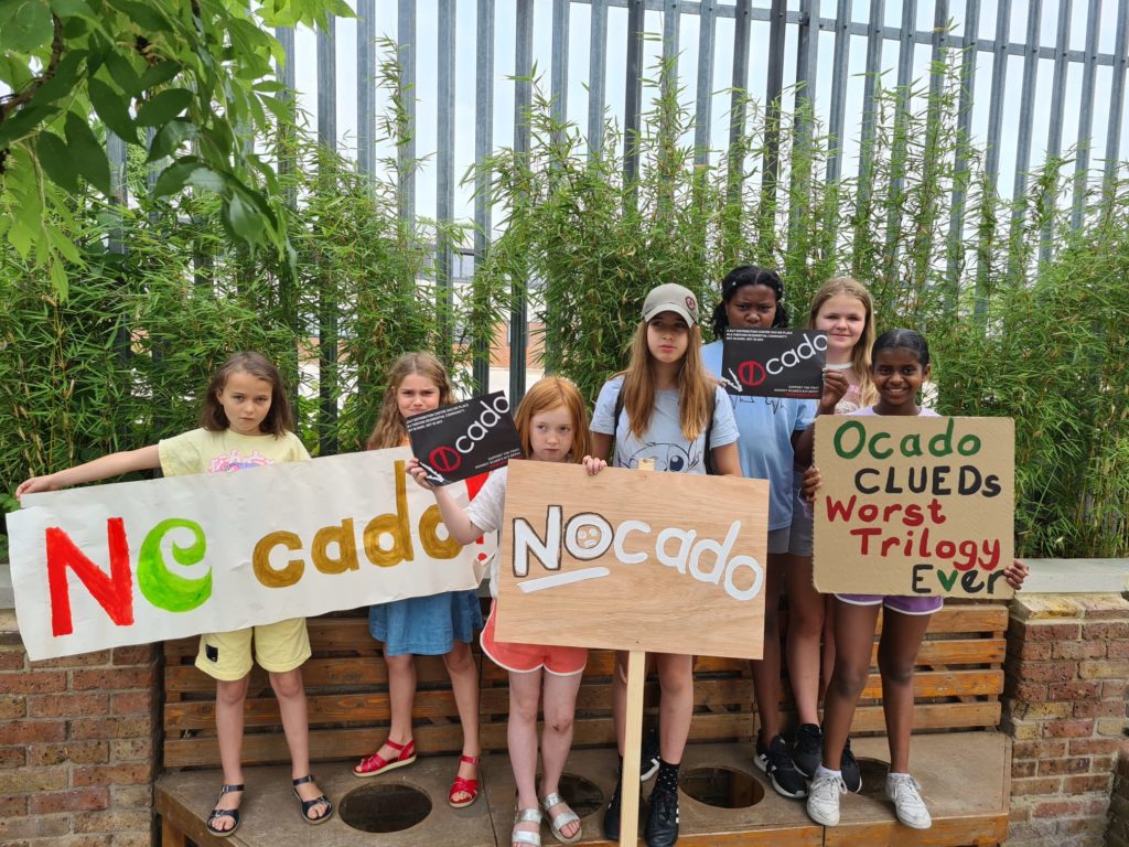 Group of girls holding signs including Ocado CLEUDs worst trilogy ever